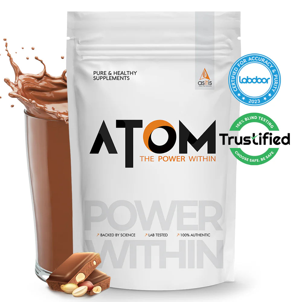 ATOM supplement package with a glass of chocolate shake and scattered pills on a white background